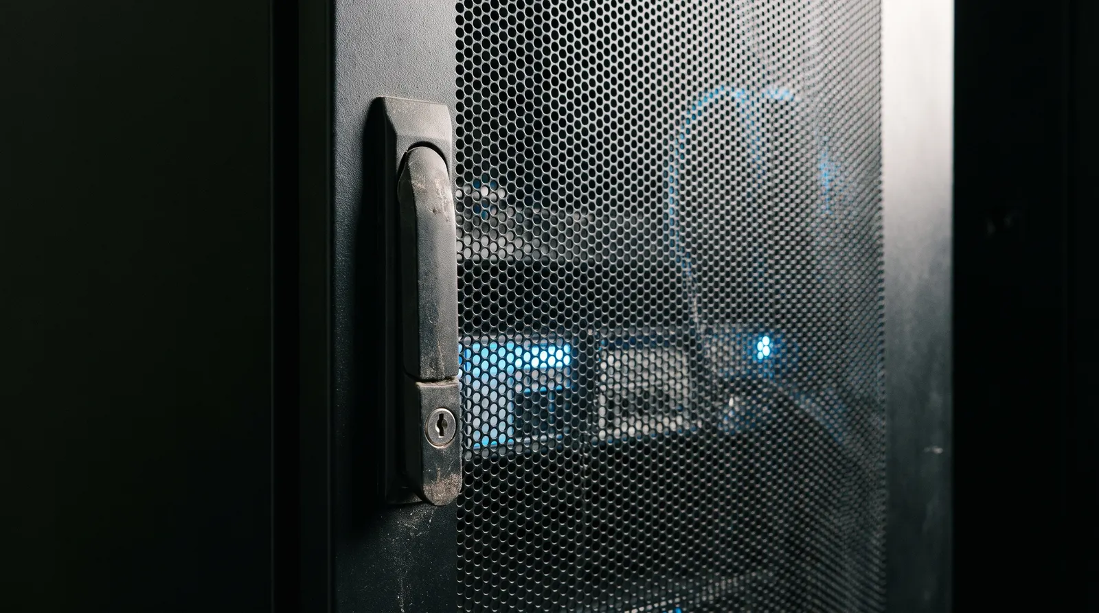 Locked steel server cabinet door, with blue light through the perforated mesh.